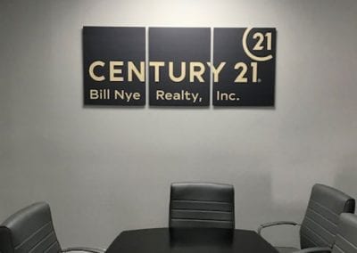 Three panel foamboard sign on the wall with Century 21 logo
